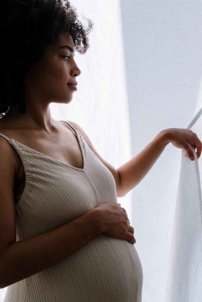 a pregnant woman parting the curtain